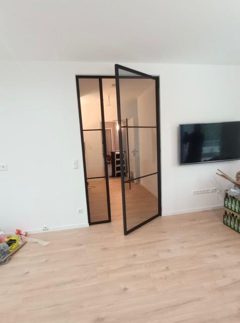 Schmale schwarze Lofttür, geöffnet ins Wohnzimmer